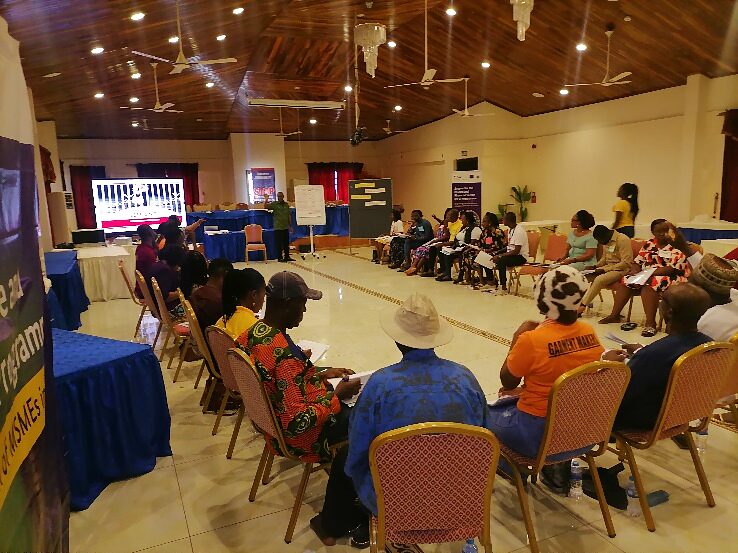 Participants seated in a public participation session with a programme banner in the background